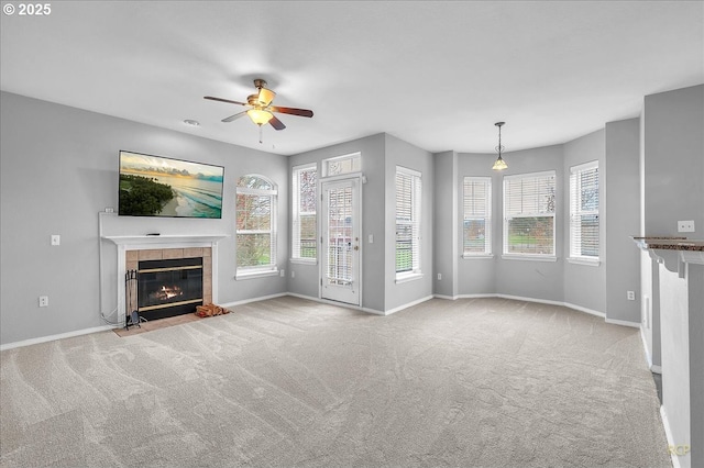 unfurnished living room featuring baseboards, plenty of natural light, carpet, and a tile fireplace