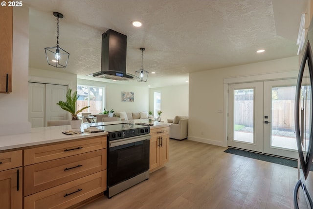 535 E St, Independence, OR 97351 - kitchen featuring appliances with stainless steel finishes, island range hood, a textured ceiling, light wood-style floors, and french doors