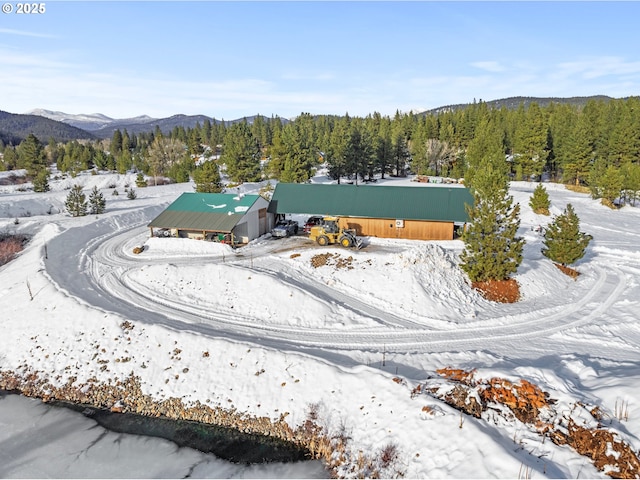 snowy aerial view featuring a mountain view and a forest view