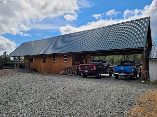 exterior space with gravel driveway, stairs, an attached carport, and metal roof