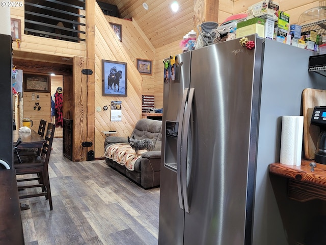 kitchen featuring wood walls, wood finished floors, lofted ceiling, stainless steel refrigerator with ice dispenser, and wood ceiling