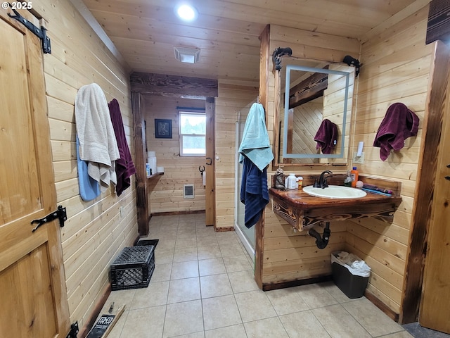 bathroom with a shower stall, a sink, tile patterned floors, wooden ceiling, and wooden walls