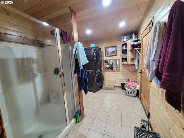 bathroom with tile patterned flooring, wood walls, wooden ceiling, stacked washer and clothes dryer, and a stall shower
