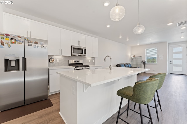 8229 SE Kinnaman St, Hillsboro, OR 97123 - kitchen with appliances with stainless steel finishes, a sink, light wood-type flooring, a breakfast bar, and tasteful backsplash