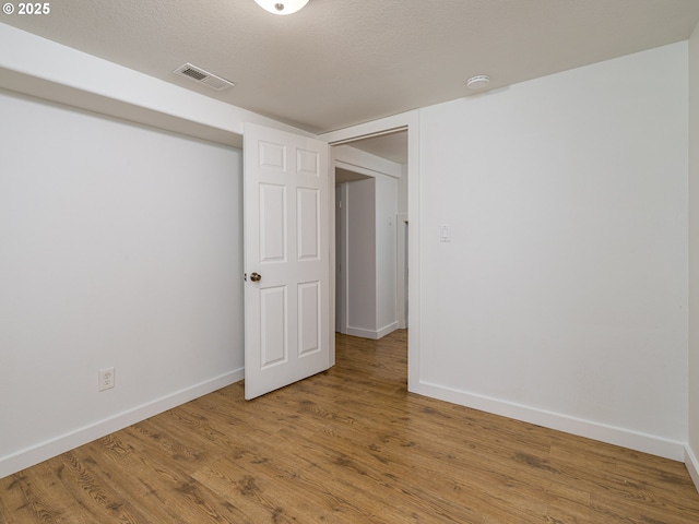 empty room with a textured ceiling and hardwood / wood-style flooring