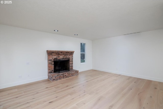 unfurnished living room featuring a fireplace and light hardwood / wood-style floors