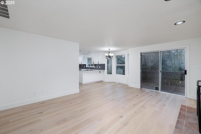 unfurnished living room featuring light hardwood / wood-style flooring and a chandelier