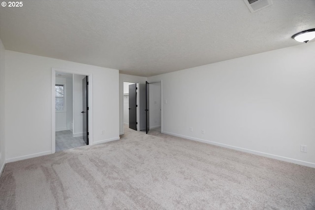 unfurnished bedroom featuring light colored carpet, a textured ceiling, and ensuite bathroom