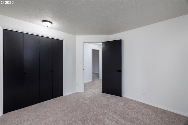 unfurnished bedroom with light colored carpet, a textured ceiling, and a closet