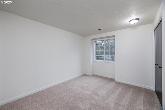 empty room with carpet and a textured ceiling