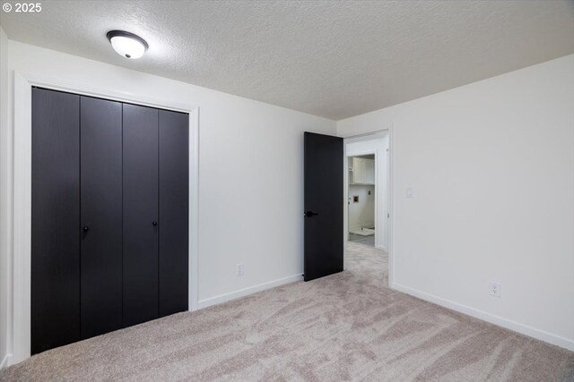 unfurnished bedroom featuring light colored carpet, a textured ceiling, and a closet