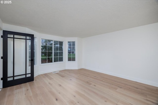 spare room featuring light hardwood / wood-style floors and a textured ceiling