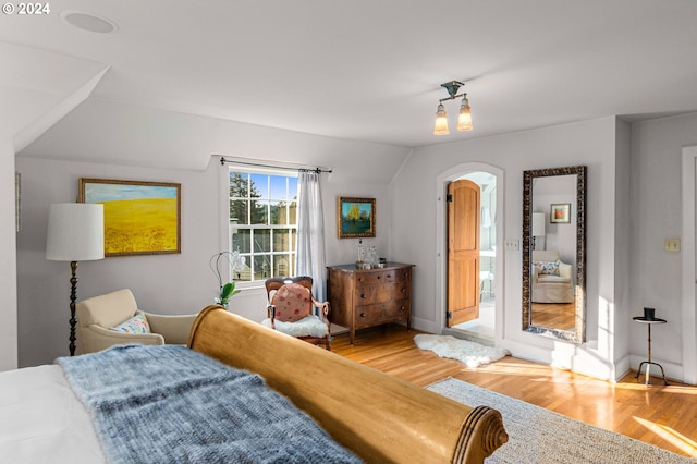 bedroom featuring light wood-style floors, baseboards, and arched walkways