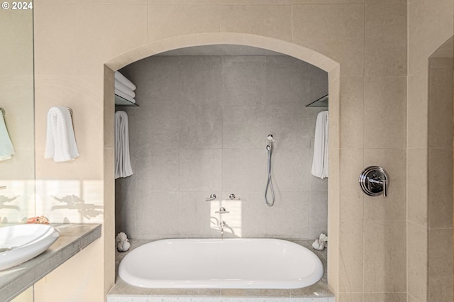 bathroom featuring a bathtub, tile walls, a tile shower, and a sink