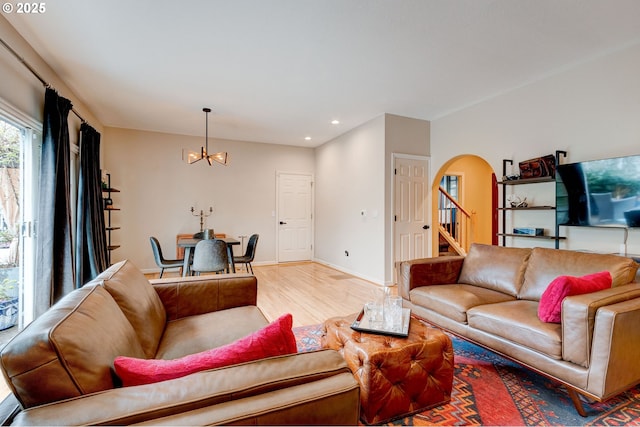 living room with arched walkways, recessed lighting, stairway, light wood-style floors, and a chandelier