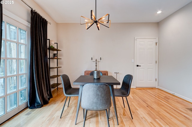 dining area featuring visible vents, light wood-type flooring, an inviting chandelier, and baseboards