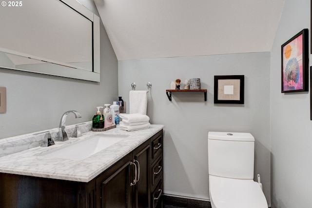 bathroom with toilet, vaulted ceiling, and vanity