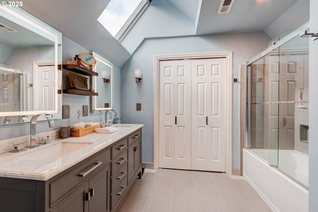 full bath featuring double vanity, vaulted ceiling with skylight, visible vents, and a sink