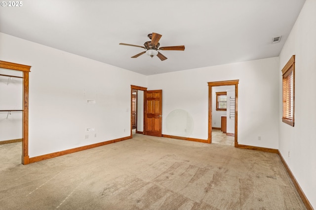 empty room with baseboards, visible vents, a ceiling fan, and light colored carpet