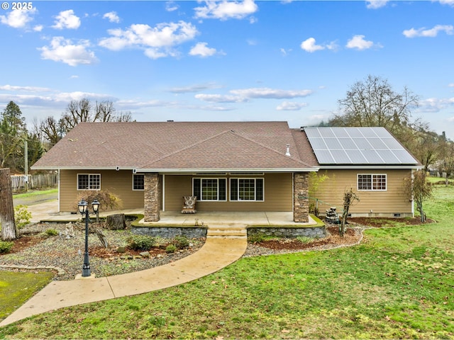 back of house featuring a yard, a patio area, and solar panels