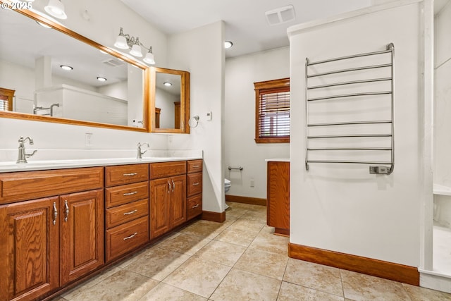 bathroom featuring double vanity, toilet, a sink, baseboards, and tile patterned floors