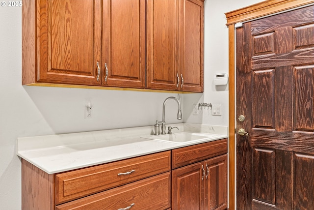 kitchen featuring light stone counters, brown cabinets, and a sink