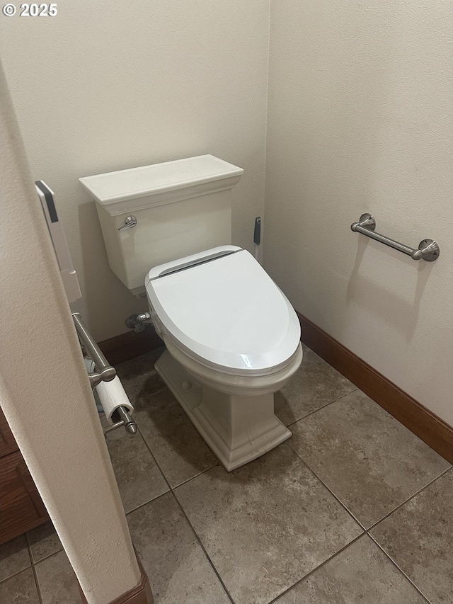 bathroom with toilet, tile patterned flooring, and baseboards