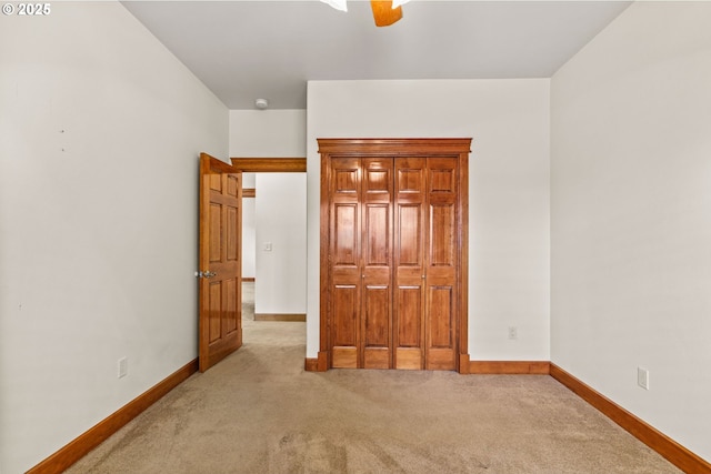 unfurnished bedroom featuring baseboards, a closet, and light colored carpet