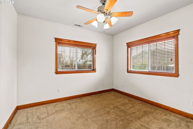 unfurnished room with carpet, visible vents, plenty of natural light, and baseboards