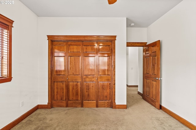 unfurnished bedroom featuring baseboards and light colored carpet