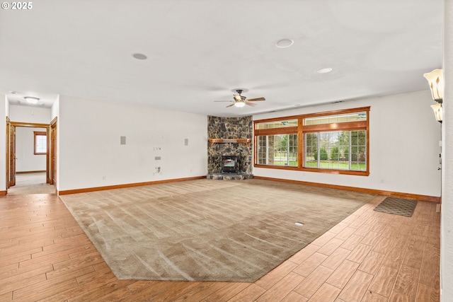 unfurnished living room featuring light wood-type flooring, baseboards, and a stone fireplace