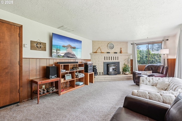 living area featuring visible vents, wood walls, a textured ceiling, a wainscoted wall, and carpet flooring