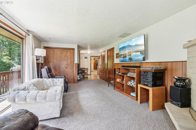 living room with carpet floors, a wainscoted wall, a textured ceiling, and visible vents