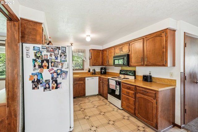 kitchen featuring white appliances, light countertops, brown cabinets, and light floors