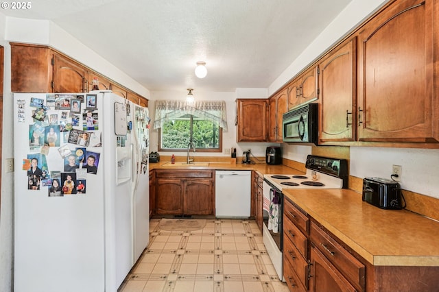 kitchen featuring a sink, light floors, brown cabinets, and white appliances
