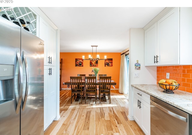 19230 Redwing Ct, Lake Oswego, OR 97035 - kitchen featuring stainless steel appliances, light wood-style flooring, tasteful backsplash, a chandelier, and white cabinets