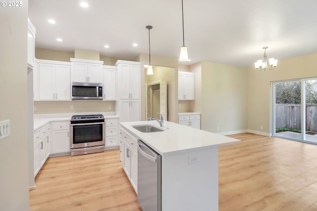 kitchen with white cabinets, stainless steel appliances, an island with sink, and pendant lighting