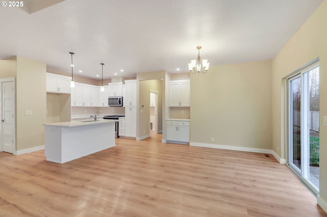 kitchen with an island with sink, light hardwood / wood-style floors, white cabinetry, appliances with stainless steel finishes, and sink