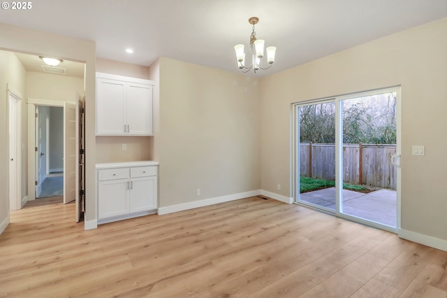 unfurnished dining area featuring a notable chandelier and light hardwood / wood-style flooring