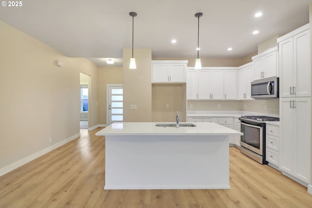 kitchen with decorative light fixtures, stainless steel appliances, an island with sink, white cabinetry, and sink