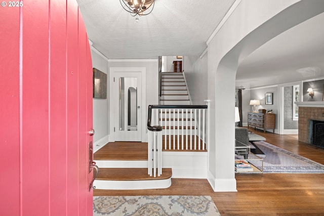 entrance foyer with dark hardwood / wood-style flooring, a fireplace, ornamental molding, and a textured ceiling