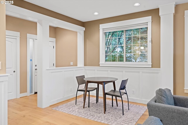 dining room featuring a decorative wall, wood finished floors, wainscoting, and recessed lighting