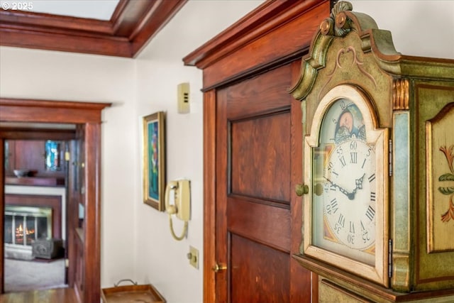 foyer with a warm lit fireplace and ornamental molding
