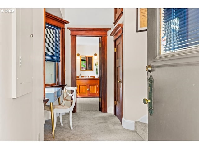 hallway featuring baseboards, a sink, and carpet