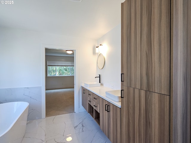 full bath featuring marble finish floors, a freestanding bath, and double vanity