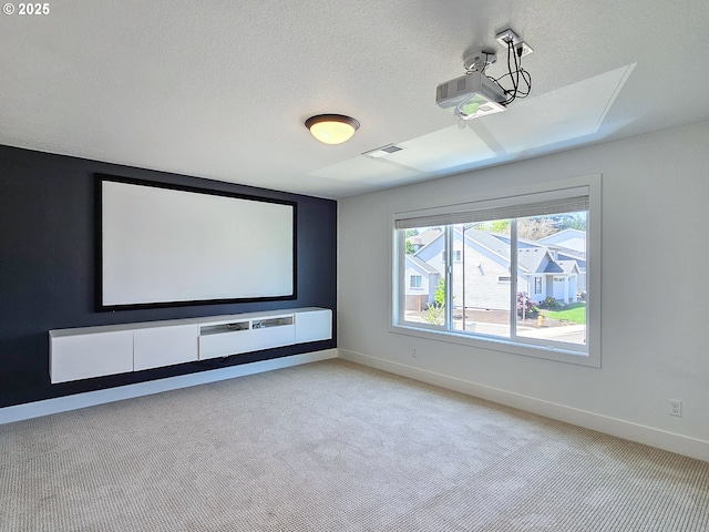home theater room featuring light colored carpet, baseboards, and a textured ceiling
