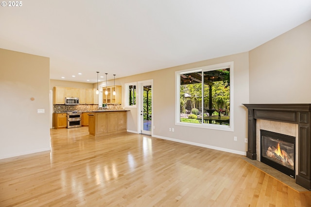 13577 SE Kisor Ct, Happy Valley, OR 97086 - unfurnished living room featuring light wood-style floors, a tiled fireplace, baseboards, and recessed lighting