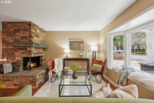 living area featuring a large fireplace, baseboards, and wood finished floors