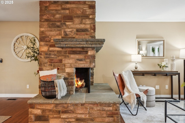 living room with visible vents, a fireplace, baseboards, and wood finished floors