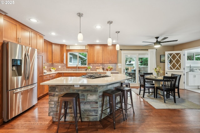 kitchen featuring stainless steel appliances, a kitchen bar, backsplash, and light countertops